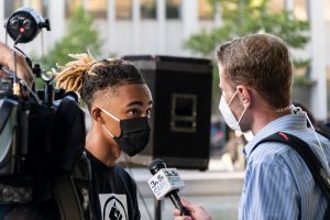 Student wearing mask being interviewed by a reporter.